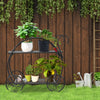 Two-tier heavy duty metal flower cart plant stand with curved handles, displaying potted plants in a garden setting.