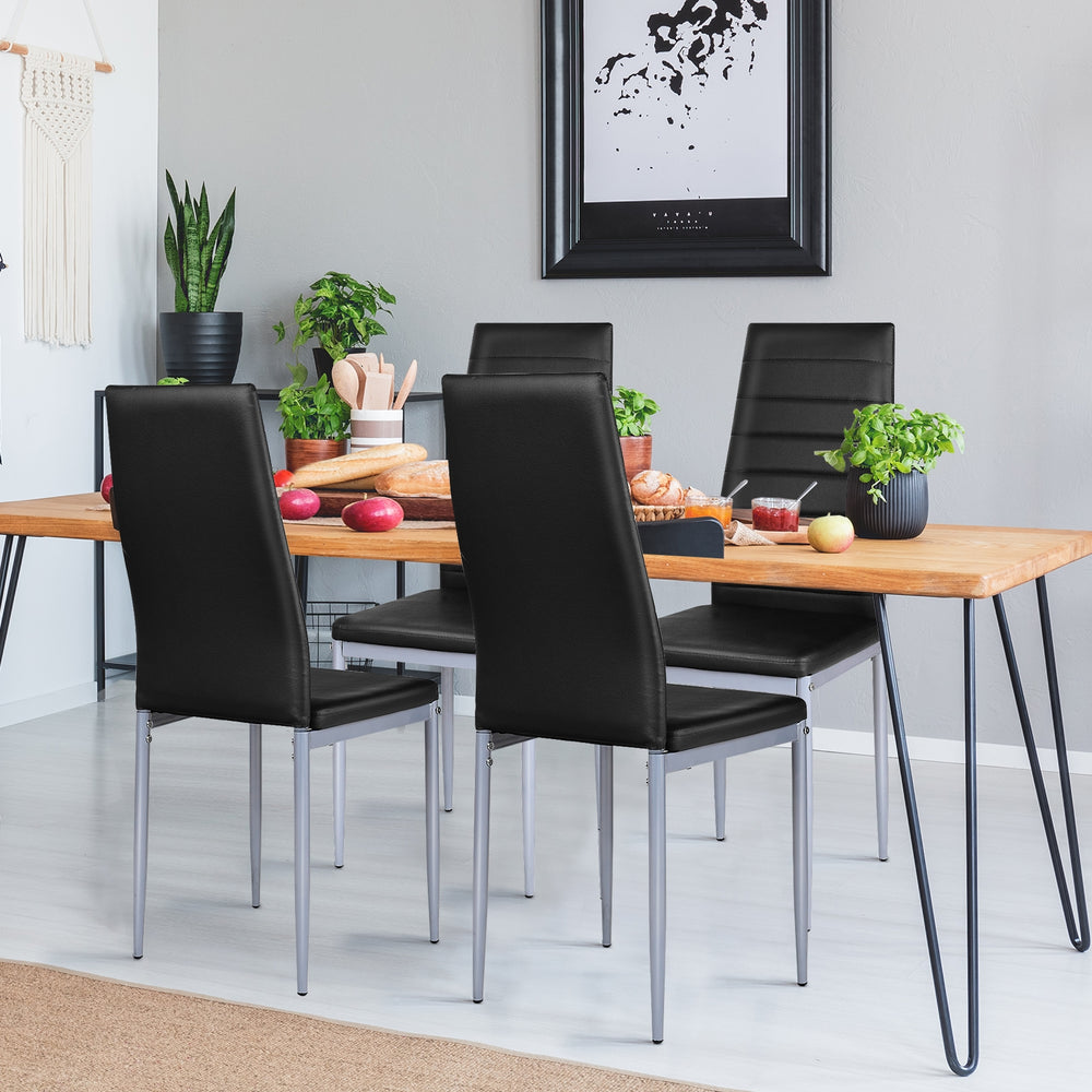 Black PVC leather dining side chairs with painted steel legs, elegantly arranged around a wooden table in a modern.