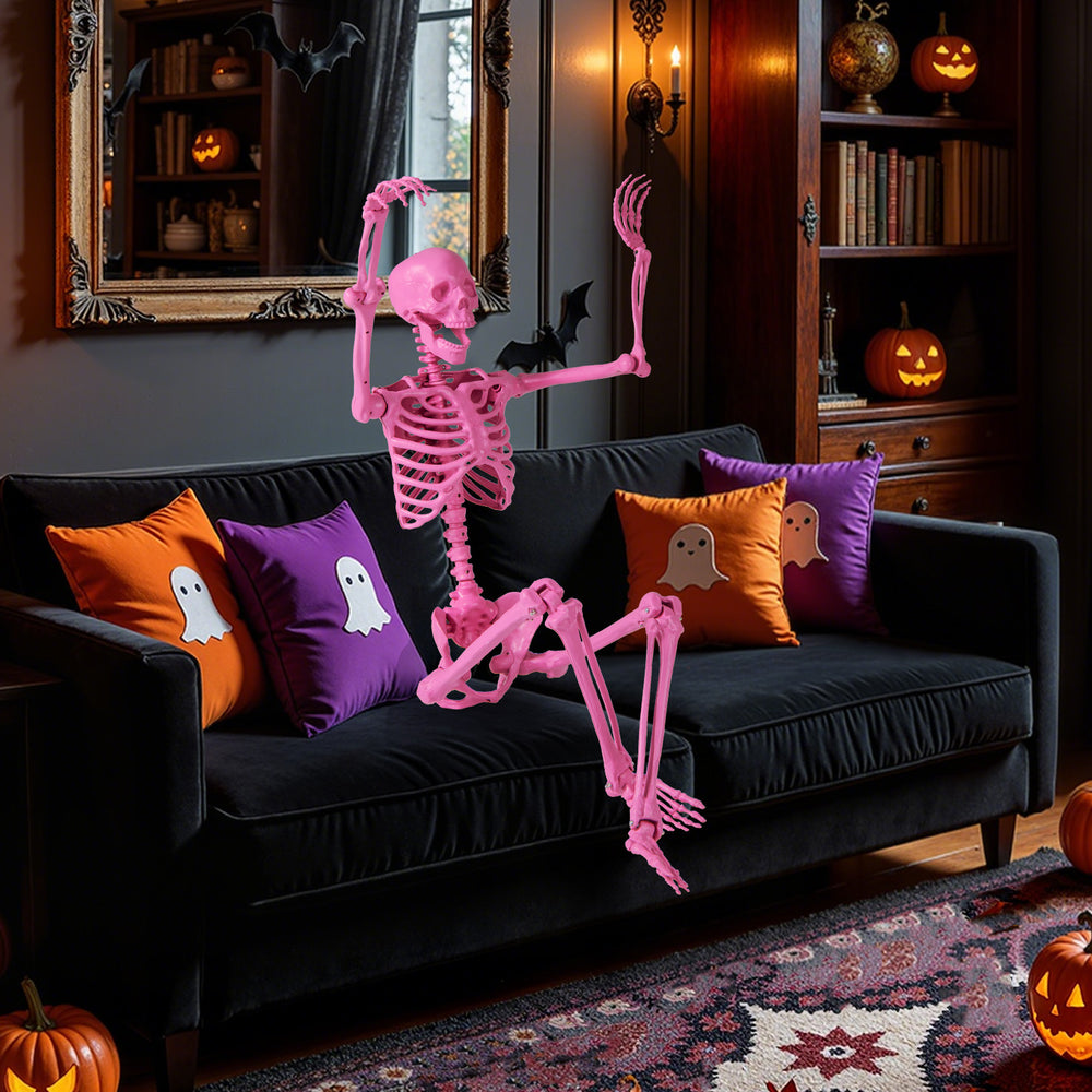 Life-size pink Halloween skeleton with movable joints, posed on a sofa with festive pillows for indoor decoration.