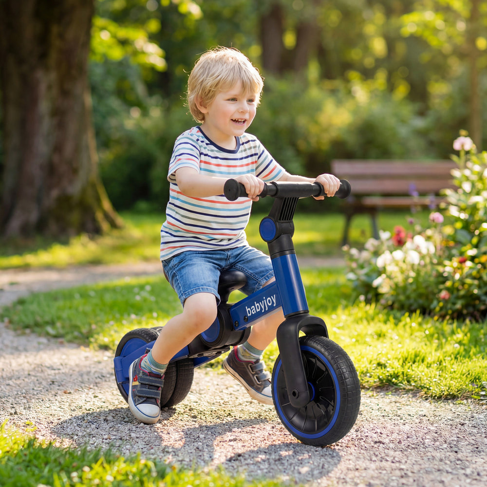 Toddler riding a blue 5-in-1 balance bike on a path, featuring removable pedals and adjustable handlebars for comfort.