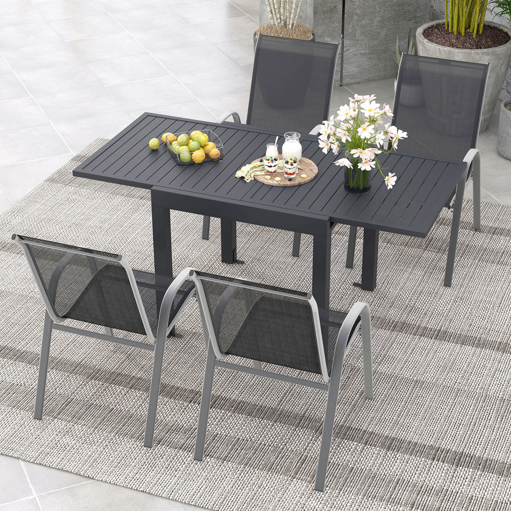 Outdoor dining table set showcasing four stackable chairs and an elegant arrangement of flowers and fruits, perfect for.