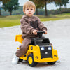 Child riding a yellow 6V electric Caterpillar construction vehicle with LED lights and detachable dump bed on a sandy.