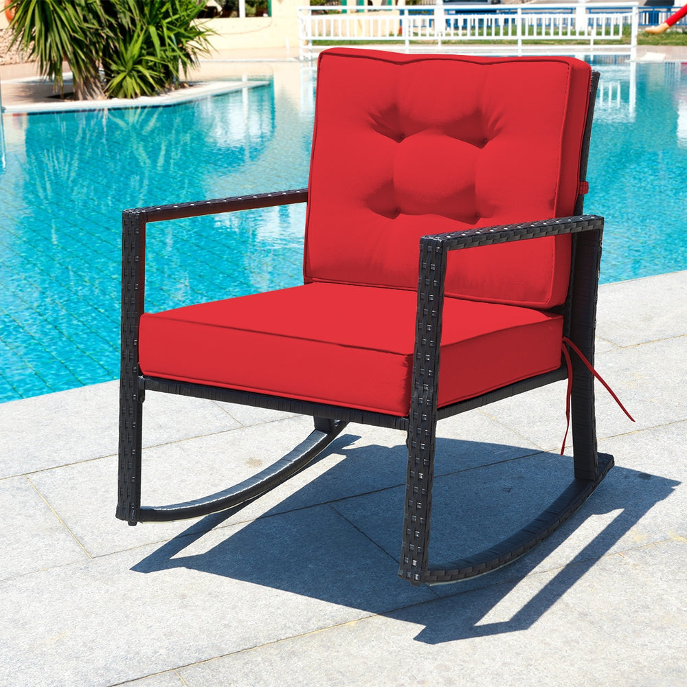 Red cushion patio rattan rocking chair with sturdy metal frame, perfect for outdoor relaxation by the pool.