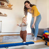 Child practicing on a blue folding balance beam with handles, designed for gymnasts to enhance balance and coordination.