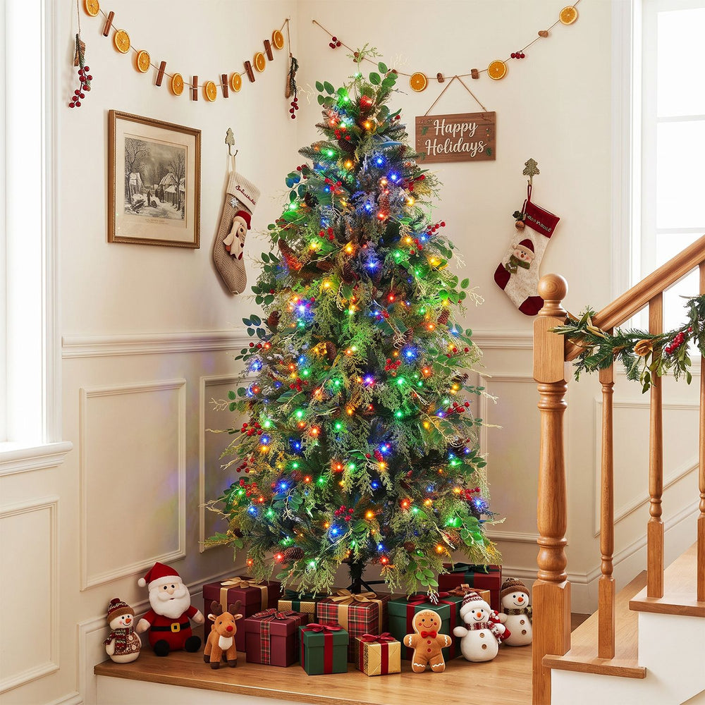 Pre-lit artificial Christmas tree with pine cones, red berries, and multicolor LED lights decorates an indoor holiday scene.