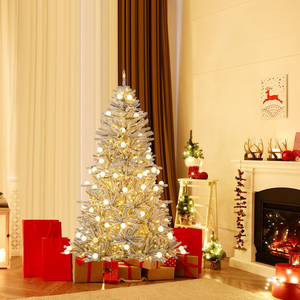 Snow-flocked 6 feet artificial Christmas tree with 81 sphere lights, set in a cozy living room with festive decorations.