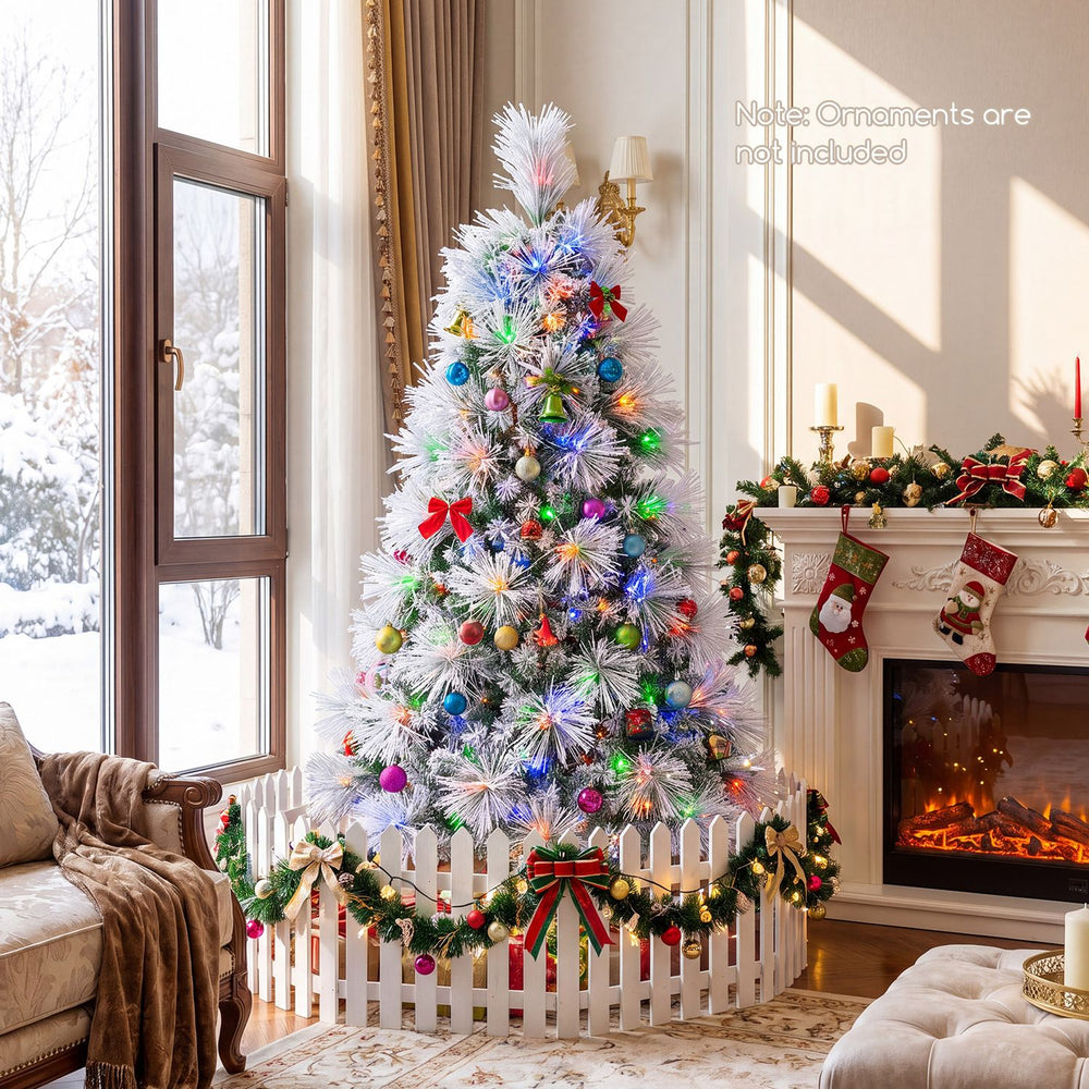Flocked pine Christmas tree with colorful pre-lit LED lights and ornaments in a festive living room.