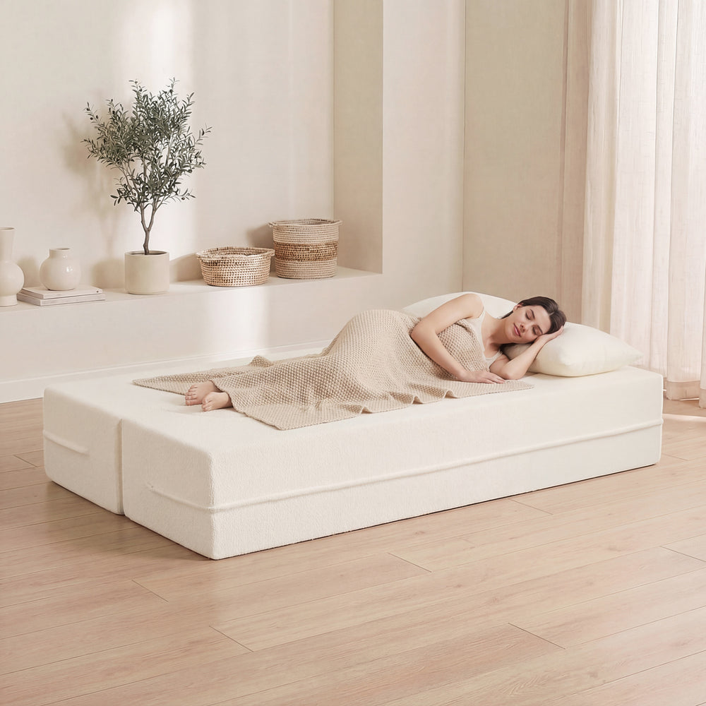 Folding sofa bed in beige with teddy fleece cover, featuring a woman relaxing with two pillows for comfort.
