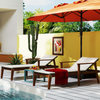 Two adjustable lounge chairs with side tables and an umbrella in a vibrant outdoor setting for relaxation.