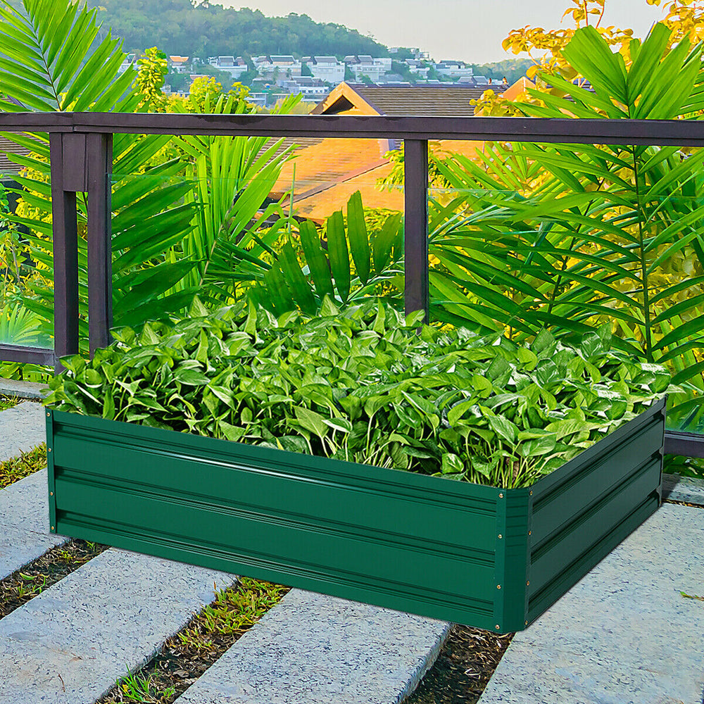 Patio raised garden bed in green with plants, ideal for growing vegetables and flowers in outdoor spaces.