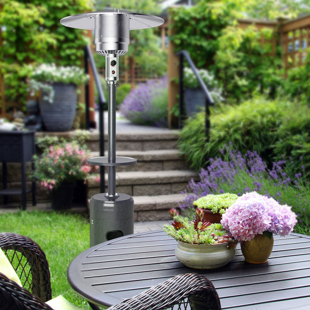 Propane standing outdoor heater in gray with table and wheels, providing warmth for patio gatherings.