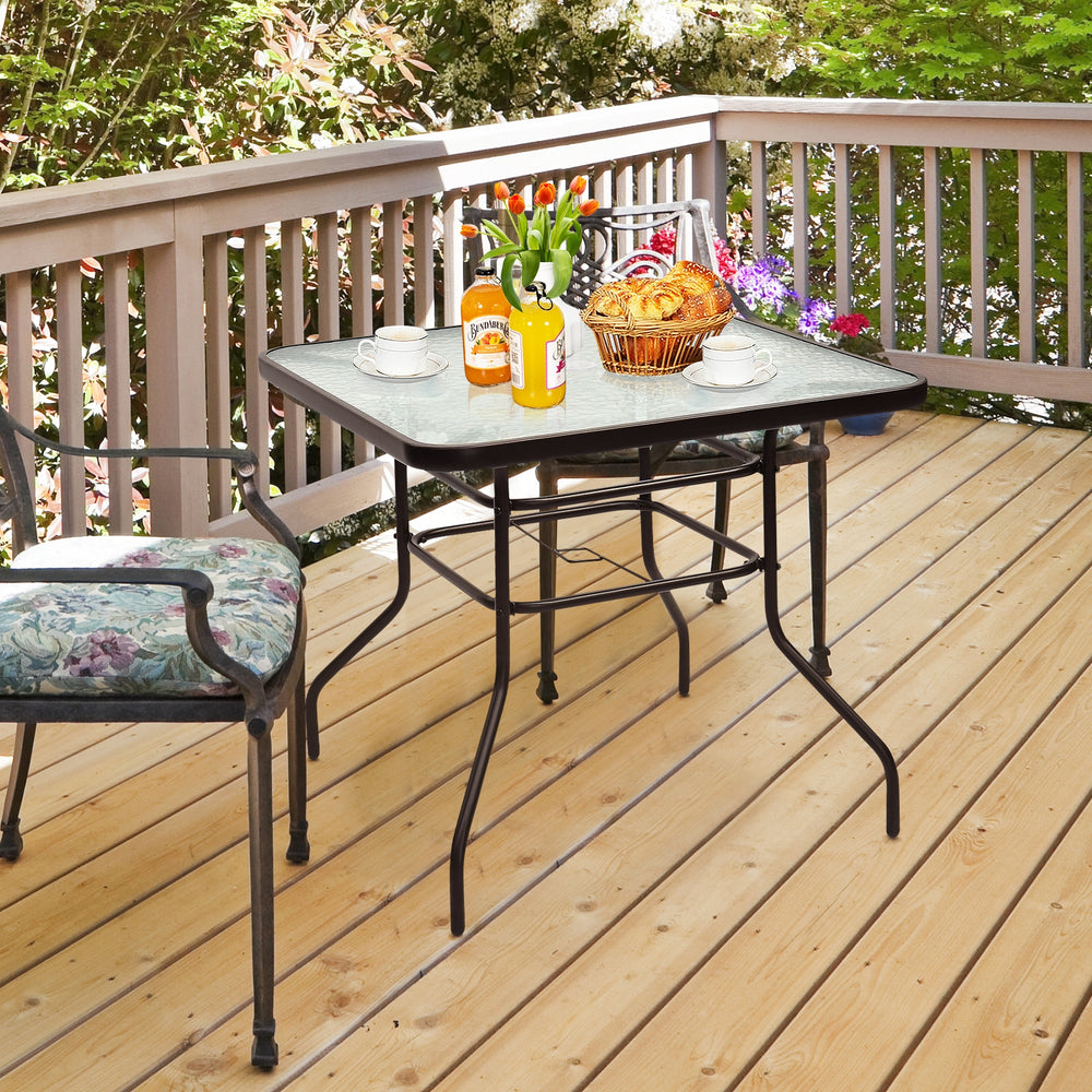 Black steel square table with tempered glass top, perfect for outdoor dining and compatible with umbrellas.