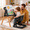 A child uses the 7-in-1 convertible high chair with adjustable tray for drawing, featuring solid wood legs and a comfortable seat.