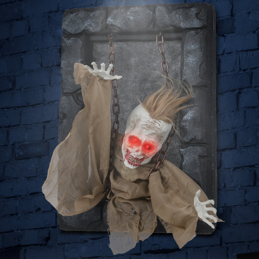 Hanging animated zombie prisoner decoration with glowing red eyes, creepy sounds, and detailed features for Halloween.