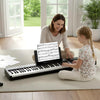 A mother and daughter play together on an 88 keys velocity-sensitive piano keyboard with a black wood texture.