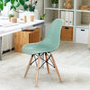 Modern green plastic hollow chair with wood legs, featuring a curved backrest for ergonomic support, ideal for dining.