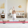 Folding gymnastics balance beam in pink with a child performing a split, featuring a sturdy pine wood frame for.