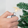 Hand using a lighter near the branches of a 9-foot premium artificial PVC Christmas tree for decoration.