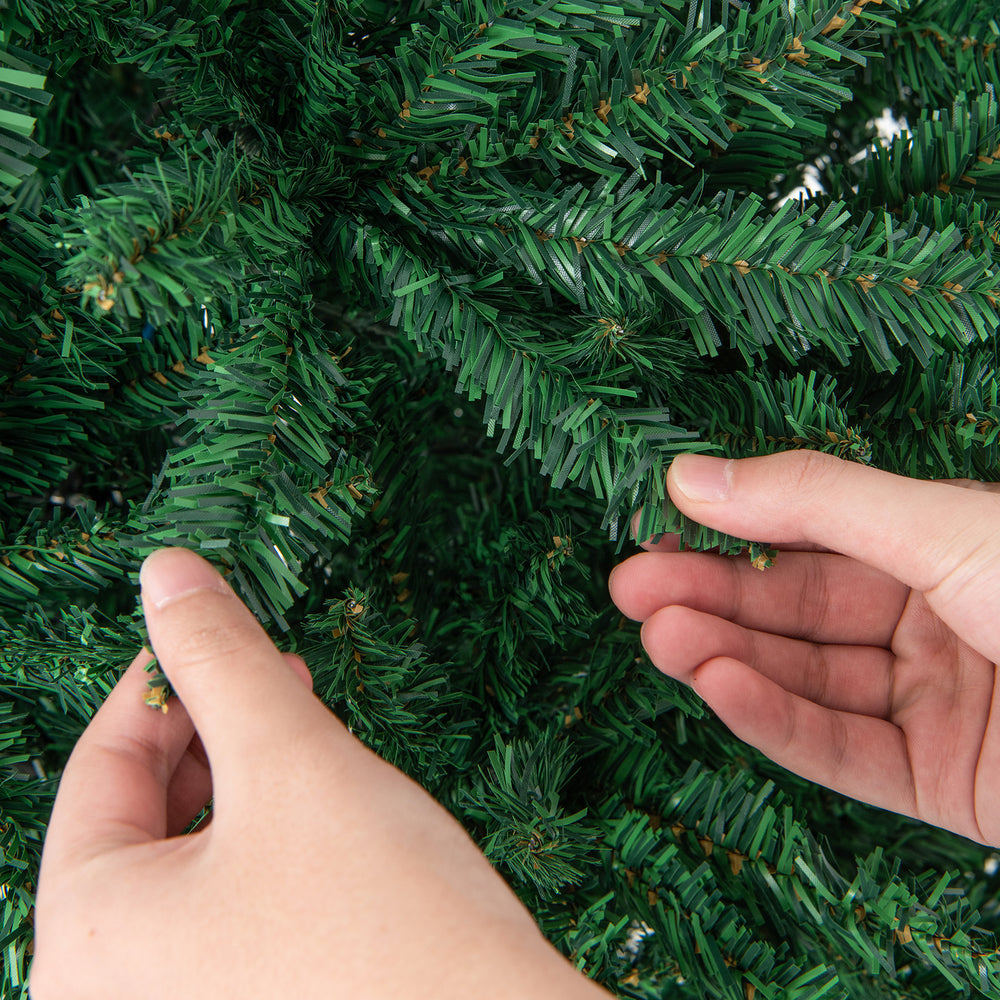 Close-up of hands adjusting the branches of a 9 feet hinged premium artificial PVC Christmas tree with lush tips.