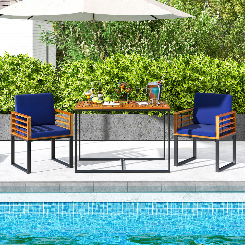 Acacia wood outdoor dining table with navy chairs, showcasing rustic style and sturdy metal frame for patio gatherings.