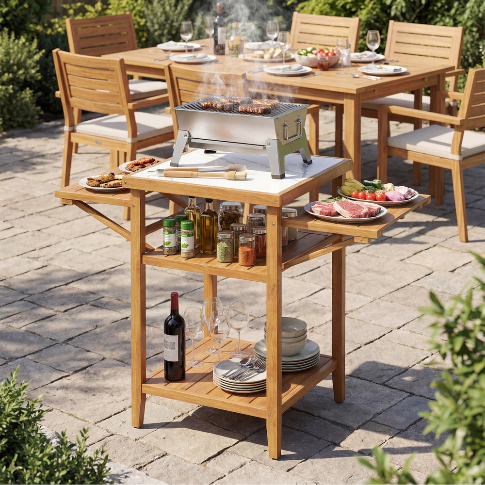 Acacia wood outdoor grill table with faux marble top, featuring drop-leaf side panels and a two-tier open shelf.