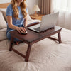 Adjustable bamboo laptop desk with tilting top and adjustable legs, perfect for working or writing in bed.