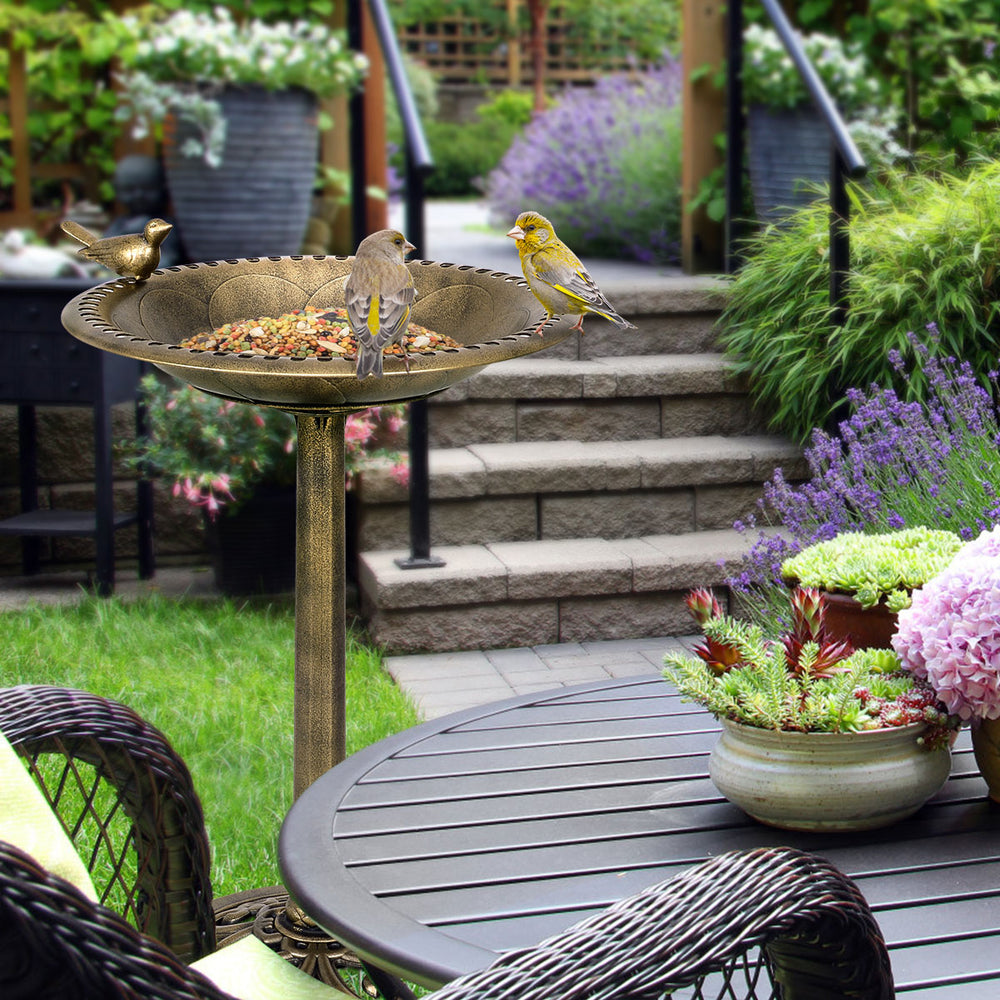 Antique gold freestanding pedestal bird bath feeder with vintage finish, attracting birds in a garden setting.