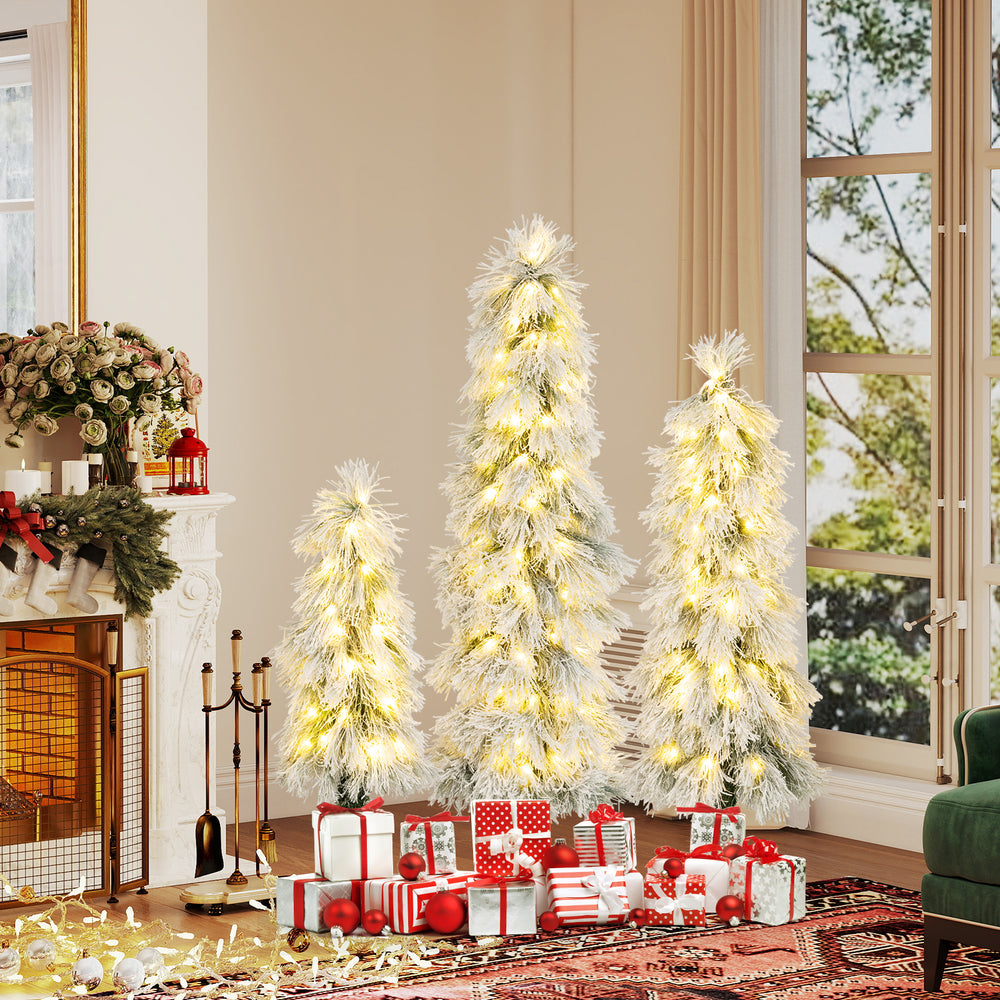Three artificial Christmas trees with snow-flocked tips and warm white LED lights, perfect for holiday decor.