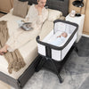Portable bedside sleeper for baby in black with adjustable heights, mesh sides, and lockable wheels for easy mobility.