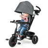 Toddler riding in a gray 4-in-1 baby tricycle with adjustable canopy and 5-point safety harness for secure outdoor fun.