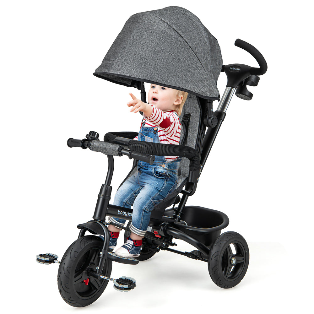 Toddler riding in a gray 4-in-1 baby tricycle with adjustable canopy and 5-point safety harness for secure outdoor fun.