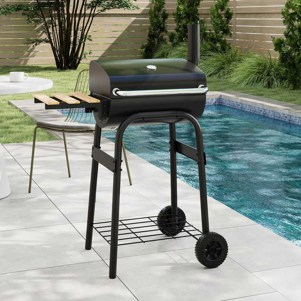 Barrel charcoal grill with foldable side table, built-in thermostat, and wheels for easy transport, ideal for backyard.