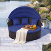 Round blue patio daybed with retractable canopy, wicker design, and pillows, perfect for outdoor relaxation by the.