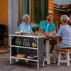 Folding camping table with 2-tier shelves, made of aluminum, ideal for outdoor BBQ and picnics, shown in use.