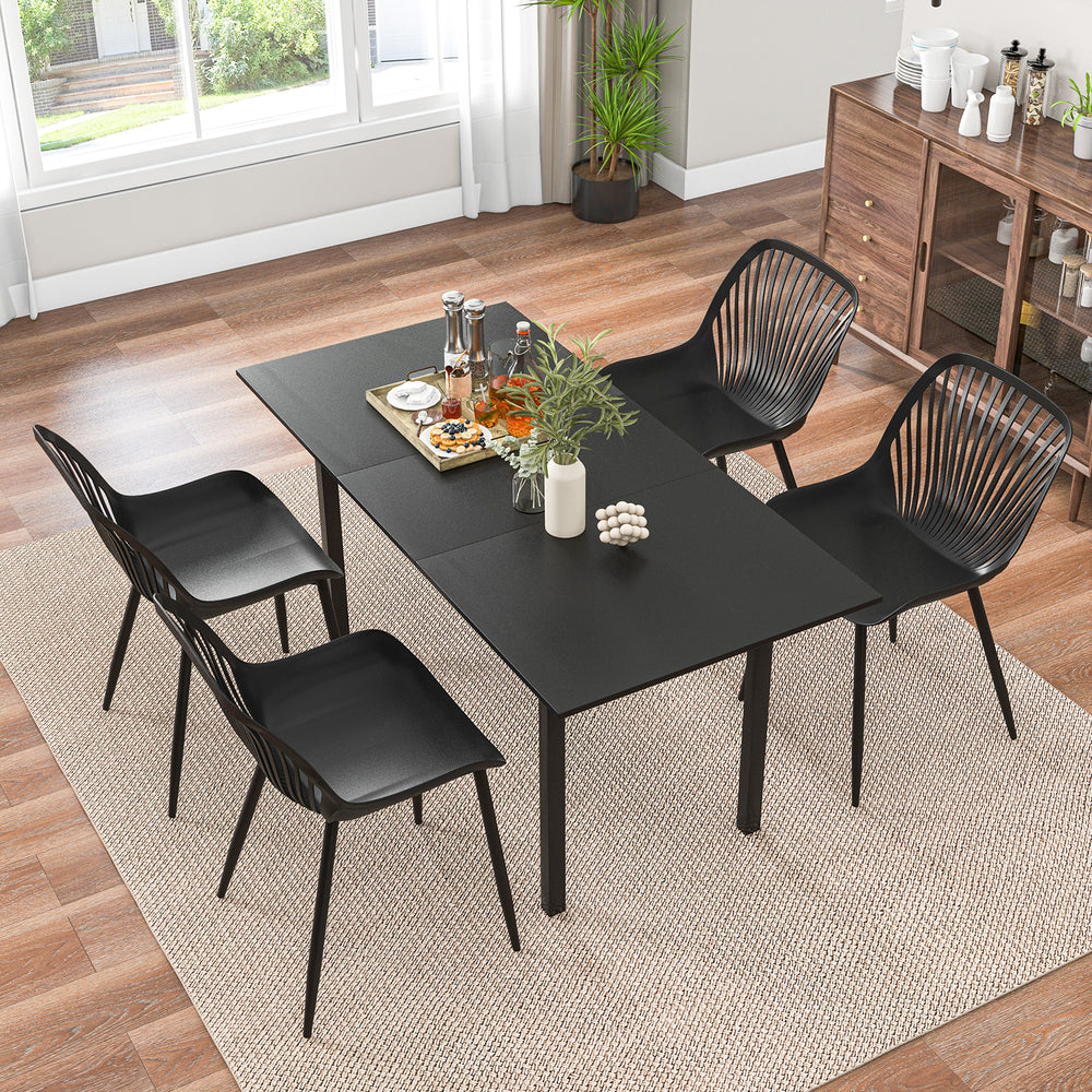 Top view of a modern dining table set with black kitchen chairs featuring metal legs and cutout backrests, perfect for.