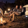 Double camping chair in black with cup holders, mesh pockets, and padded seats, ideal for outdoor relaxation by the.