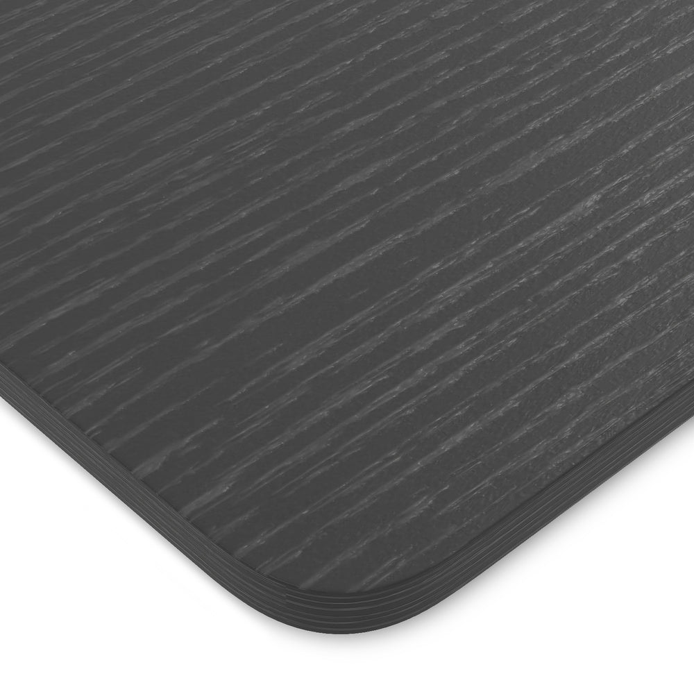 Close-up of the black tabletop for an electric standing desk, featuring a smooth surface and rounded corners for.