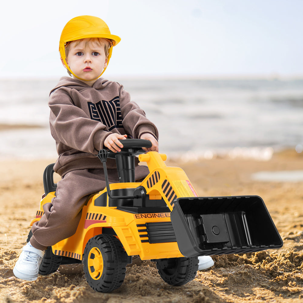 Child riding a yellow excavator digger toy with adjustable bucket on the beach, promoting outdoor play and physical.