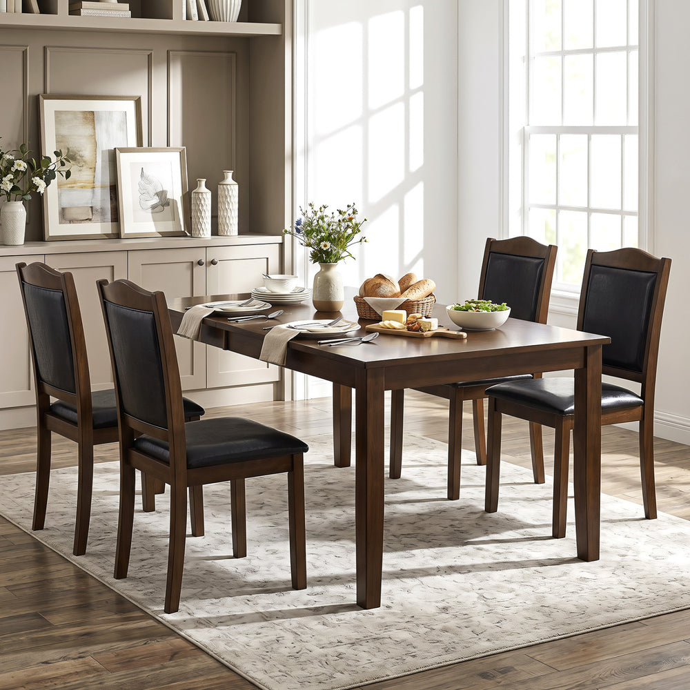 Set of four walnut dining chairs with faux leather upholstery and padded seats, perfect for rustic and modern dining spaces.