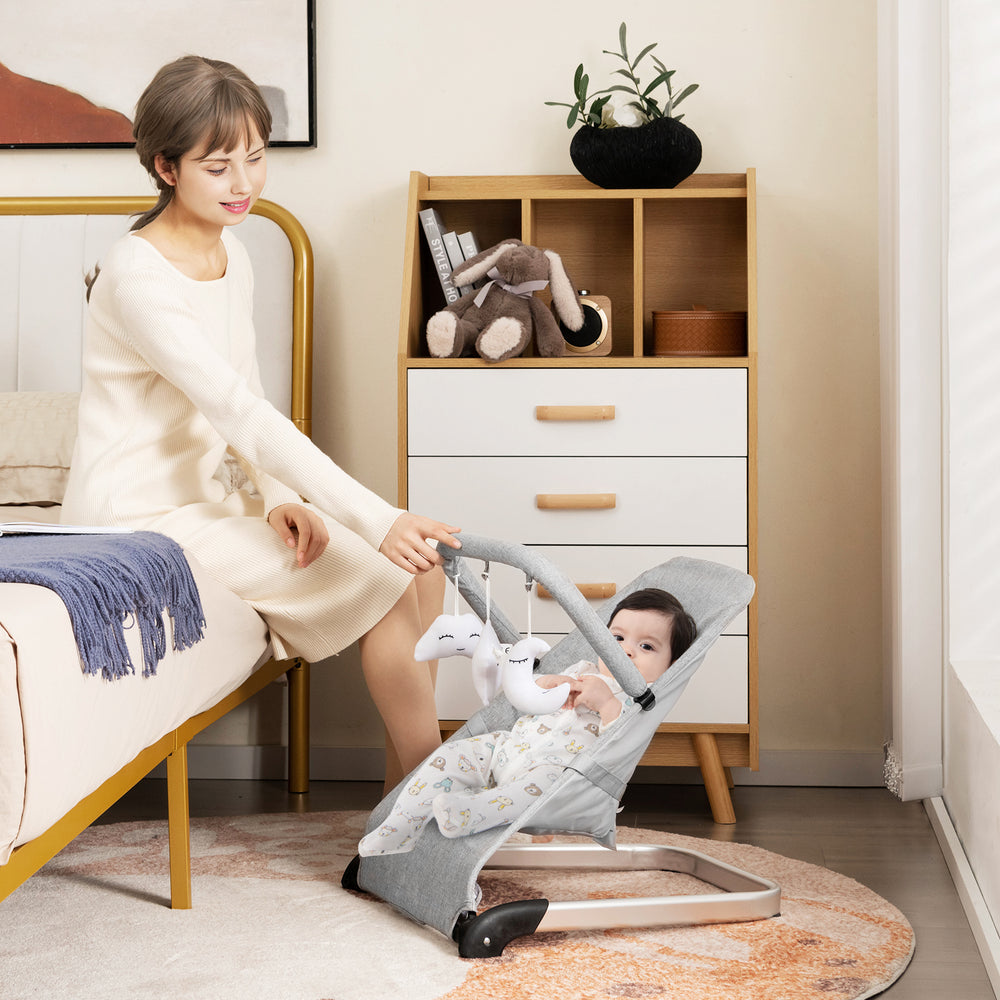 Foldable baby bouncer in gray, featuring a soft ergonomic seat, sturdy metal frame, and adjustable safety harness for.