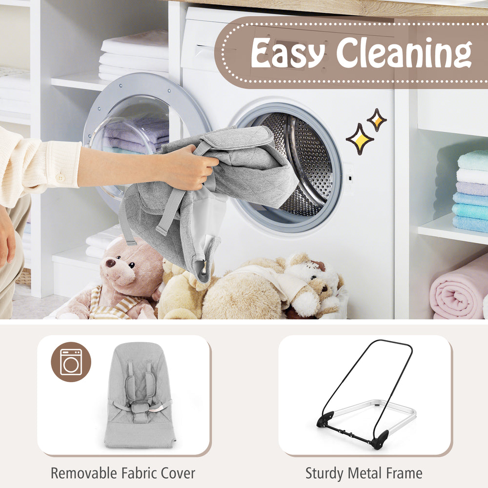 Foldable baby bouncer in gray with removable fabric cover, shown being placed in a washing machine for easy cleaning.