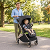 Foldable baby stroller in black with shock-absorbing wheels, ideal for smooth rolling on various terrains like cobblestones.