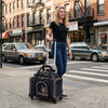 Foldable pet carrier with wheels, shown in use on city streets, offers easy access and a comfortable space for small pets.