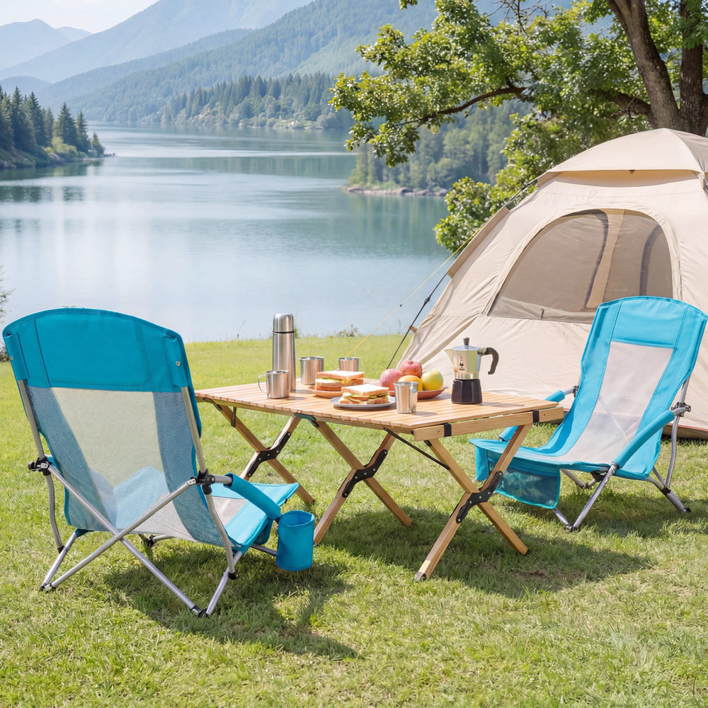 Two blue folding beach chairs with padded armrests set up by a lake, perfect for camping and outdoor relaxation.