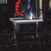 Folding welding table with a tiltable tabletop, 4-level height, and wheels for easy mobility in a workshop setting.