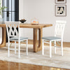 White folding wooden dining chairs with faux leather upholstery, featuring X-shaped backs, ideal for small spaces.