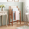 Freestanding solid wood towel rack with teak oil finish, featuring three tiers for organized bathroom storage.