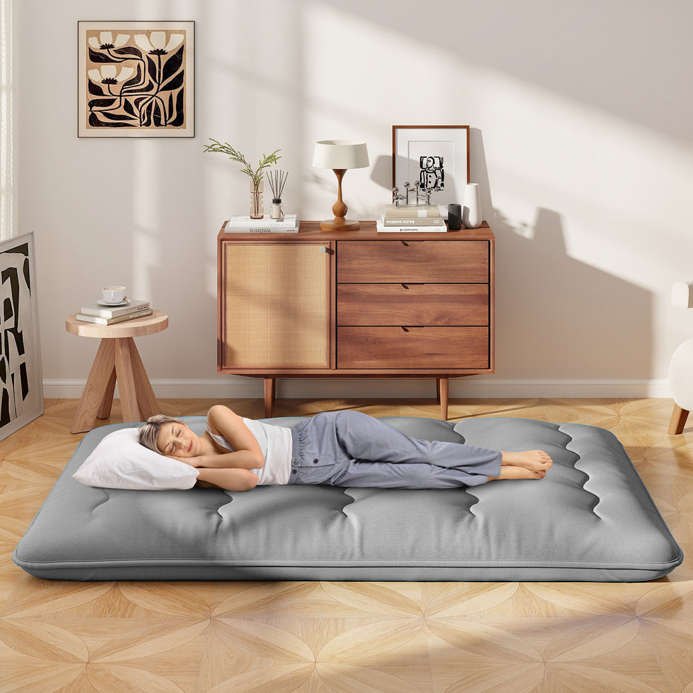 Full-size futon mattress with a washable cover, shown in a cozy room, ideal for sleeping, camping, or yoga.