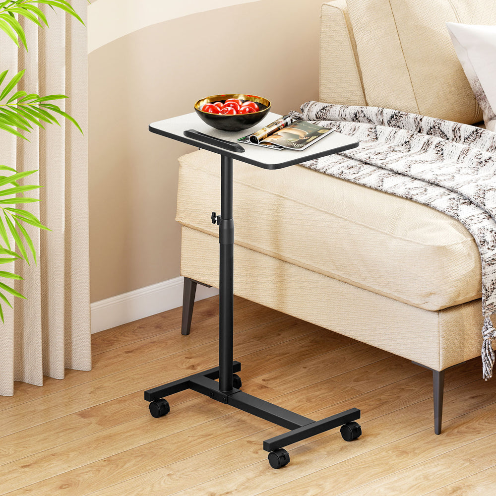 Gray overbed rolling table with adjustable height, 360° rotating tabletop, and wheeled base for easy mobility.
