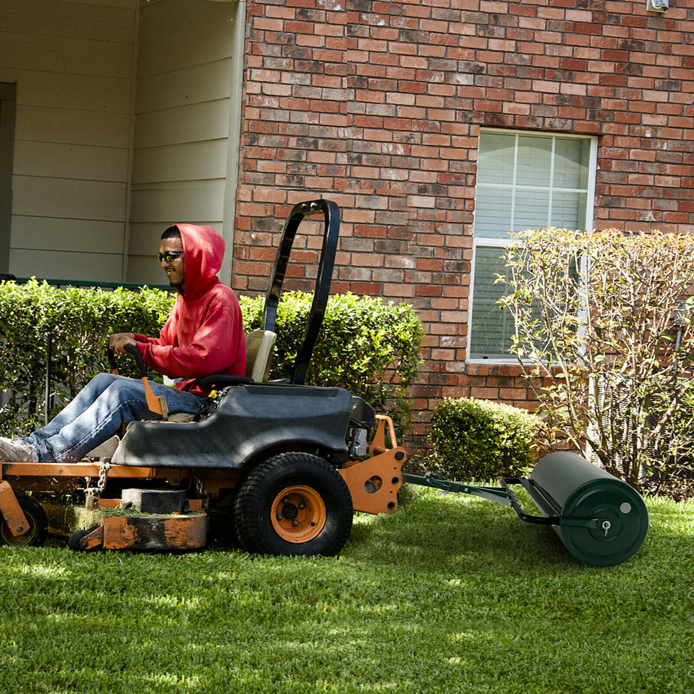 Metal lawn roller with detachable gripping handle, 17-gallon capacity, used for flattening lawns in a yard.